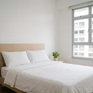 A made bed with white linen in a sunlit bedroom